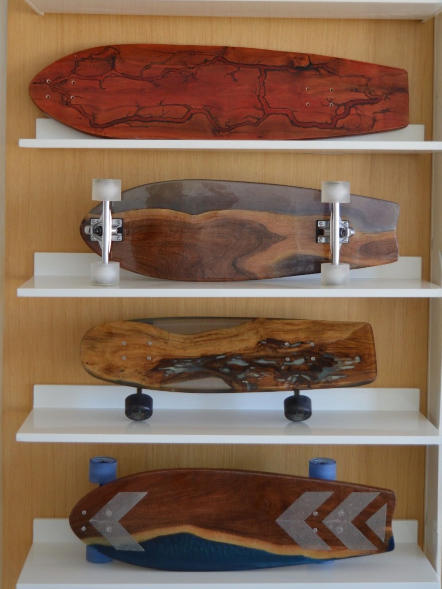 Collection of One of None resin longboards displayed on white wall shelves