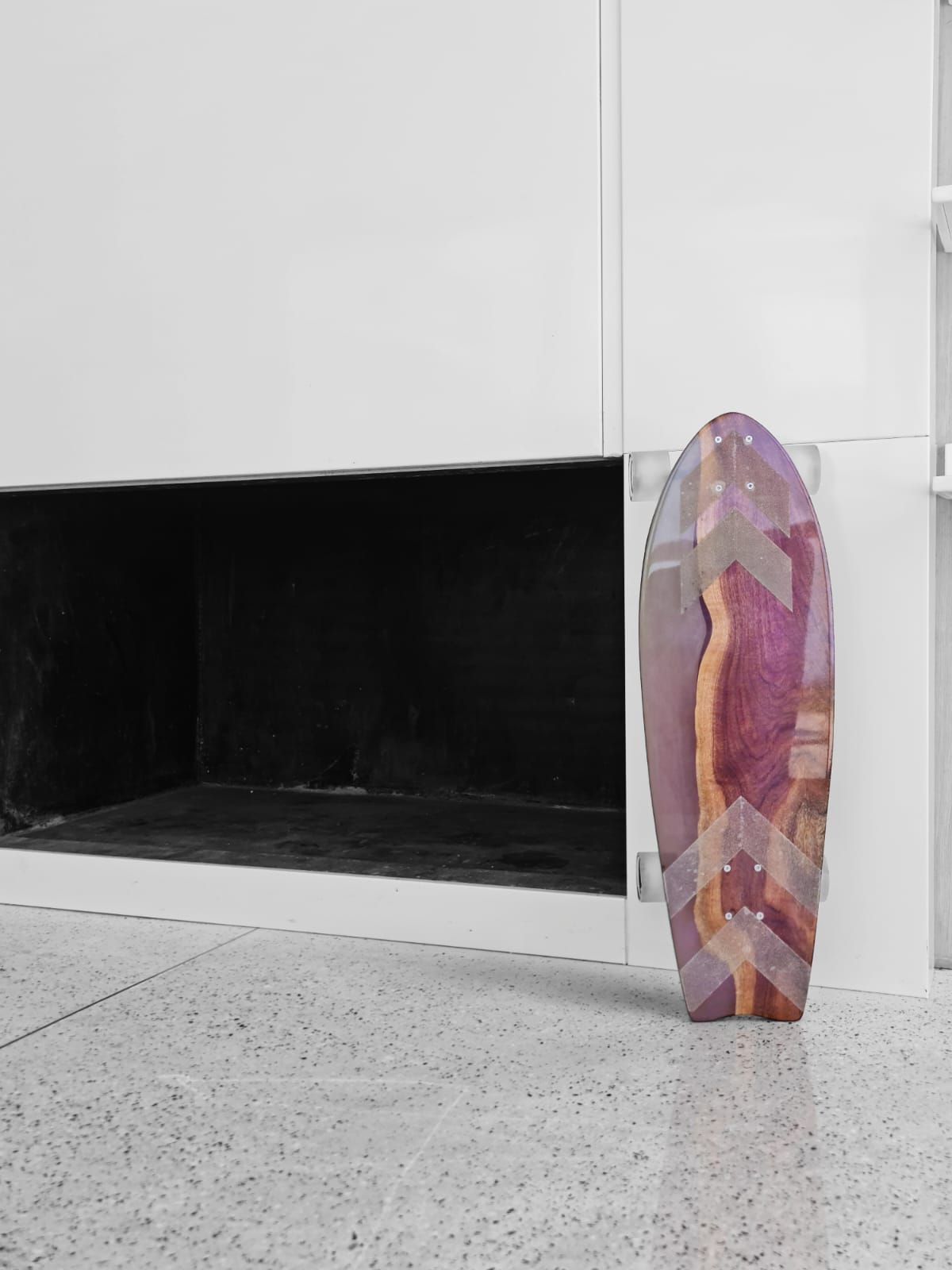 Chevron resin longboard leaning against a white cabinet on speckled floor