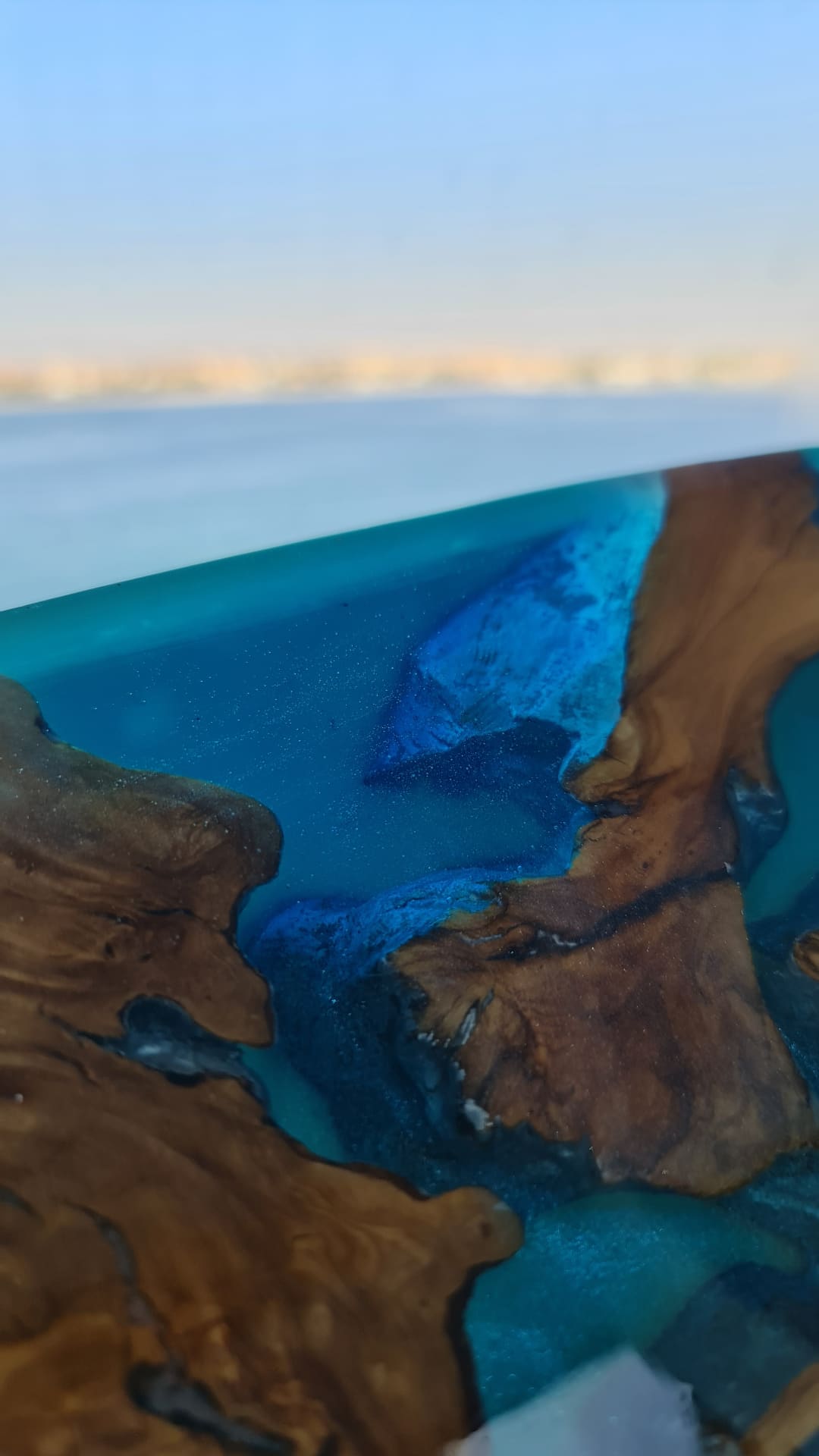 Lunar Drift longboard close-up with luminous blue resin and wood fragments