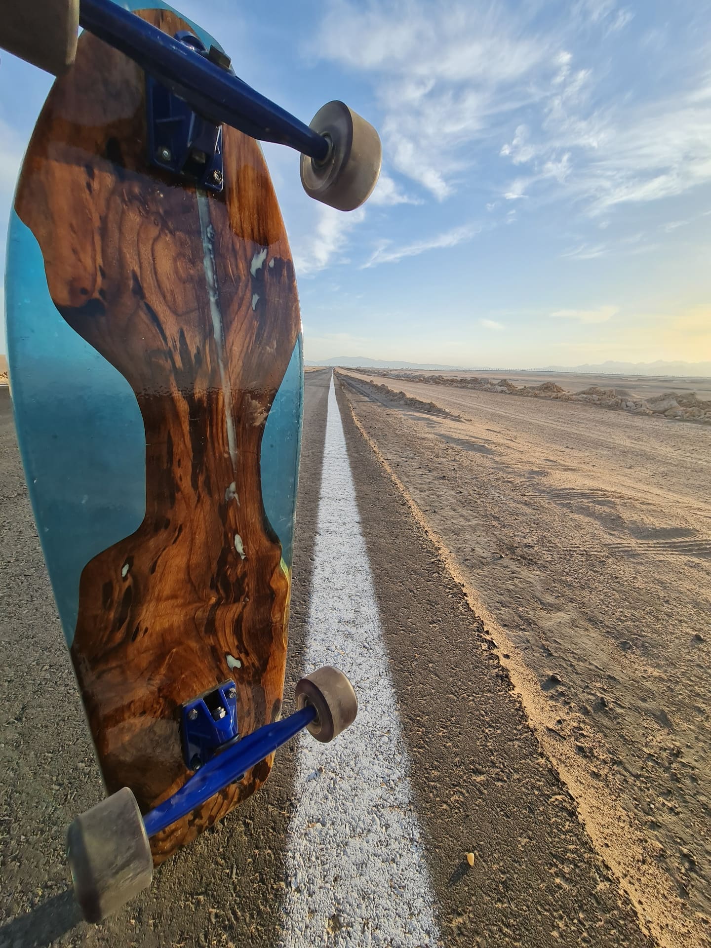 Close-up of Tide Runner longboard tip with blue resin and natural wood grain on a clean background
