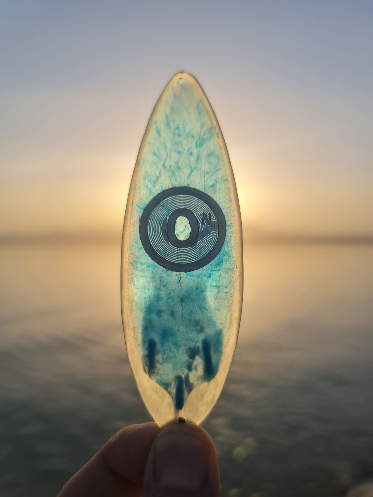 Resin surfboard miniature against ocean sunset